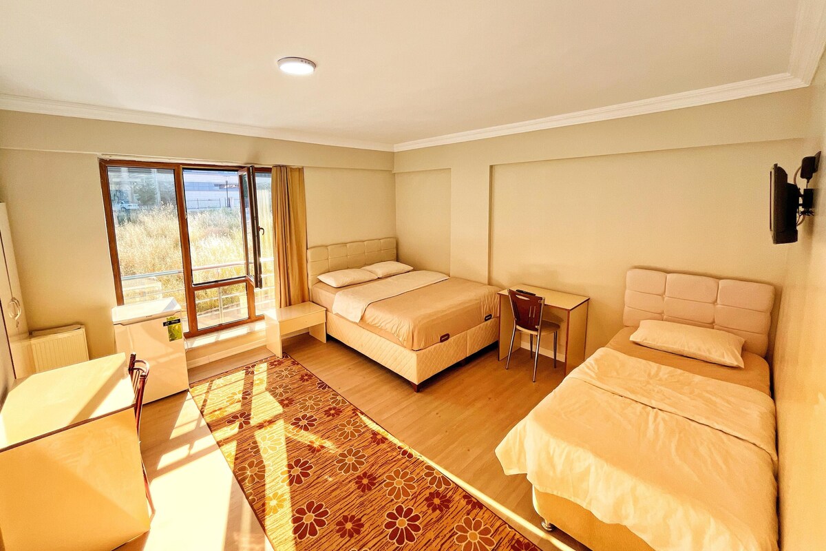 Ein Hotelzimmer mit zwei Betten, einem Schreibtisch, einem Stuhl und einem großen Fenster mit Aussicht.