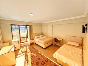 Ein Hotelzimmer mit zwei Betten, einem Schreibtisch, einem Stuhl und einem großen Fenster mit Aussicht.