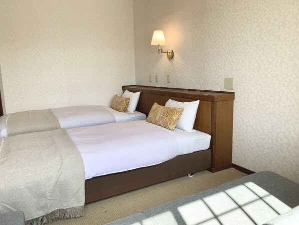 A double bed with a wooden headboard, two pillows, and a bedside lamp.