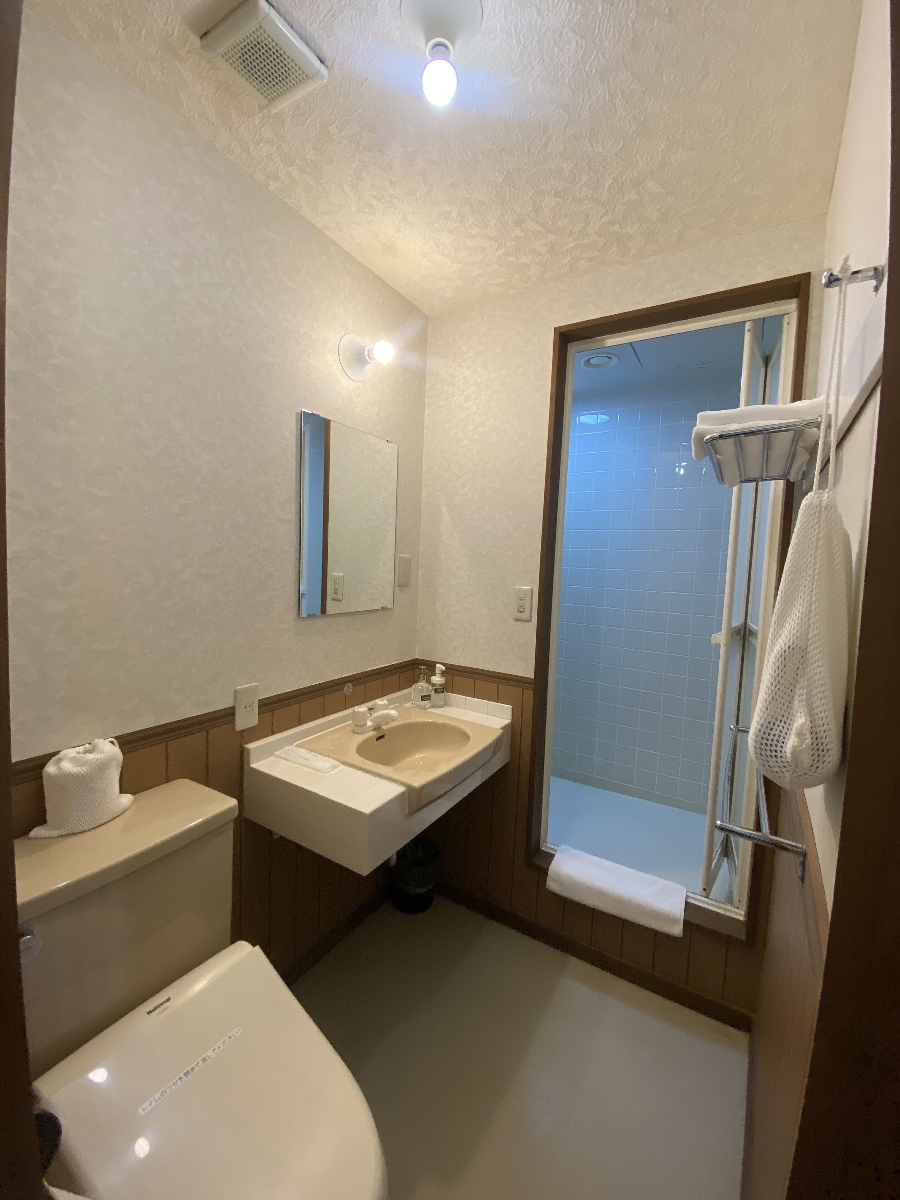 A compact bathroom with a toilet, sink, and shower.