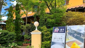A garden area with potted plants and a pathway leading to a building with a yellow facade. - samurise NORTH (Fujikawaguchiko)