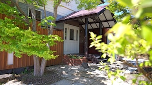 A house with a covered porch, a brick flower bed, and a wooden fence. - samurise NORTH (Fujikawaguchiko)