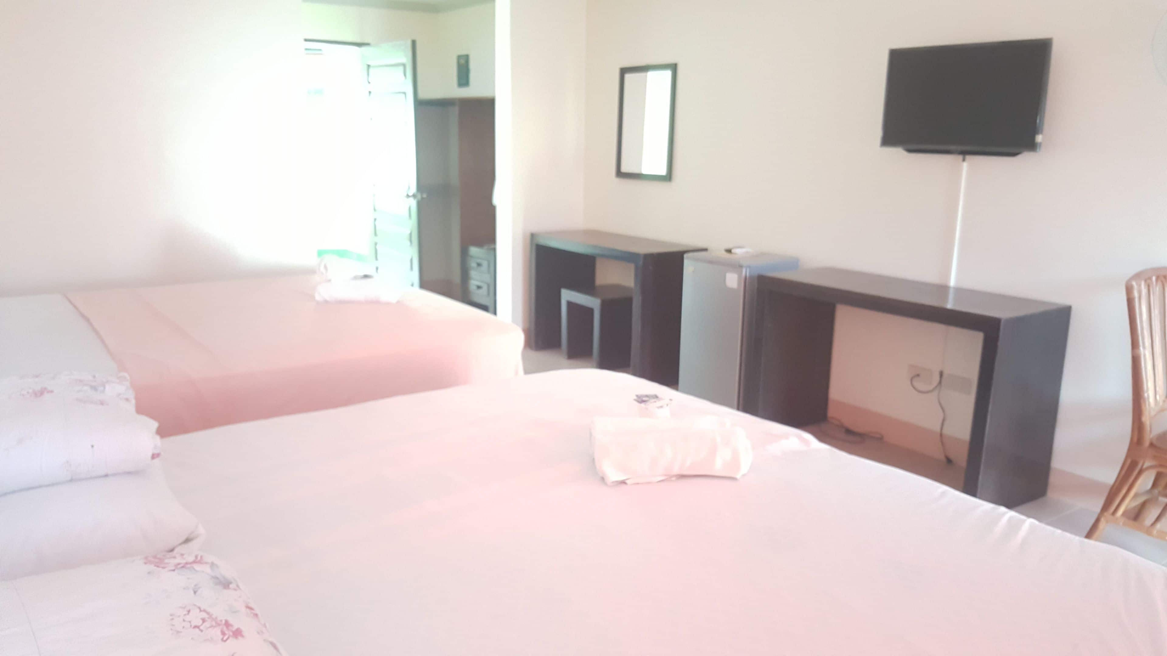 Une chambre d’hôtel avec deux lits, un bureau, une chaise, une télévision et un miroir.