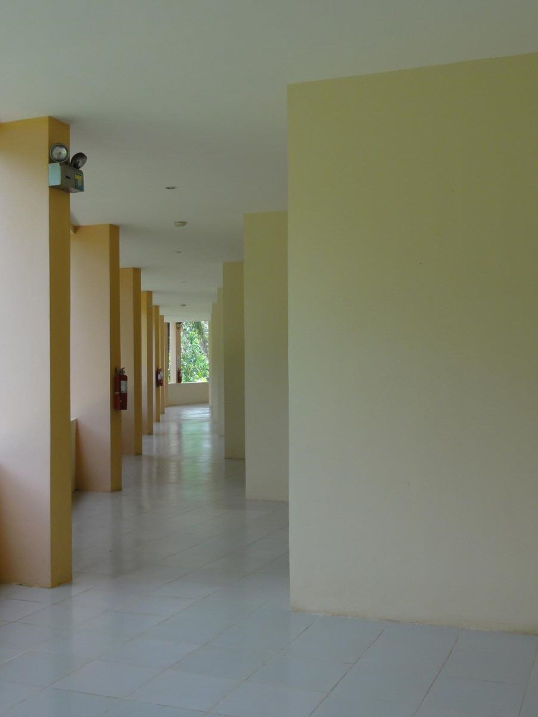 A long, narrow corridor with evenly spaced columns and a tiled floor.