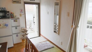 A compact kitchen with a microwave, refrigerator, and a small dining area. - Pine House in Churaumi (Motobu)