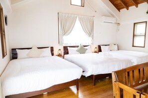 A hotel room with two beds, wooden floors, and a wooden bench.