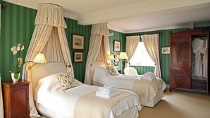 A hotel room with two beds, a wooden wardrobe, and a large window with curtains. - Weir Cottage (Chipping Norton)