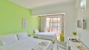 A hotel room with two beds, a desk with a chair, a TV, and a balcony with a view of the outside.