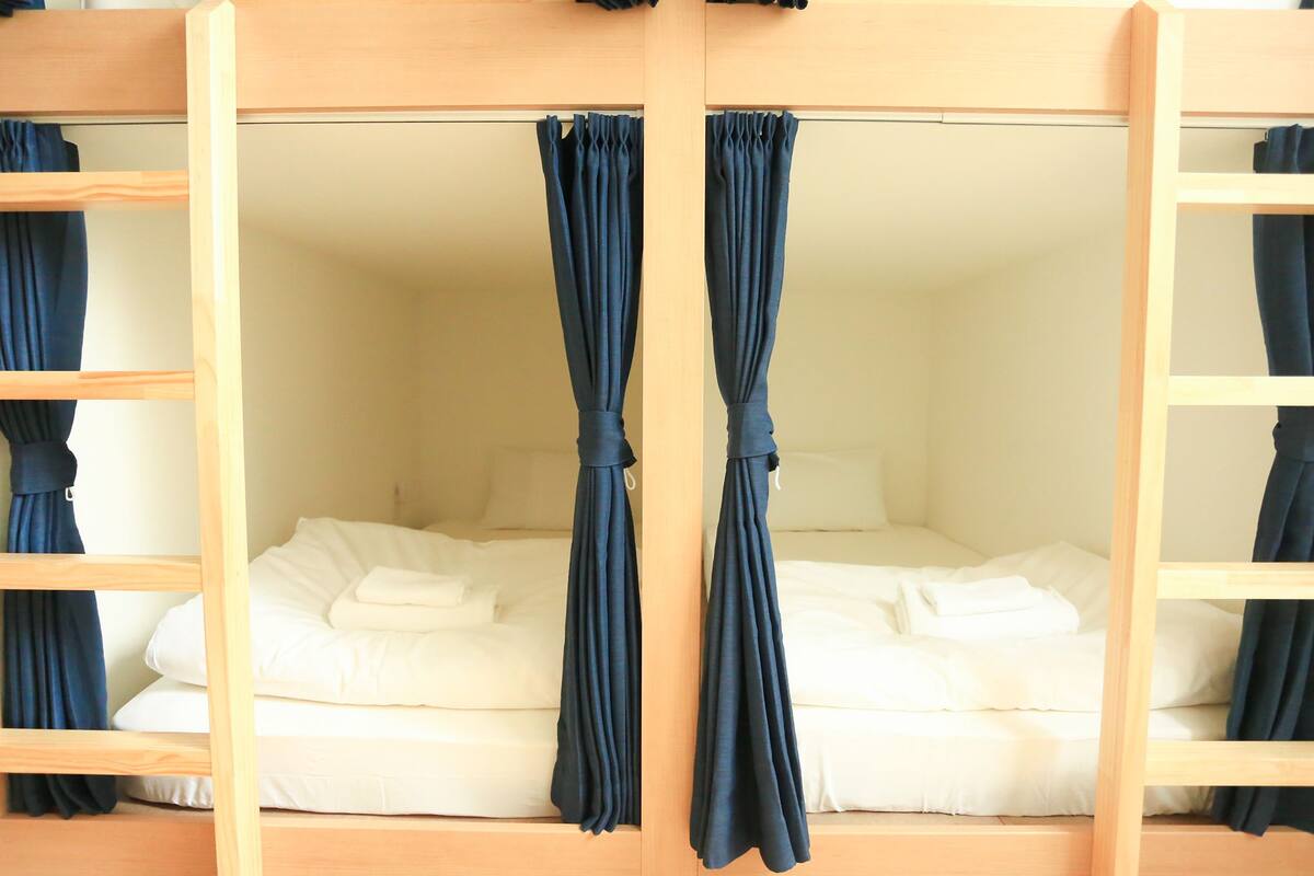 A bunk bed with a white mattress and blue curtains.