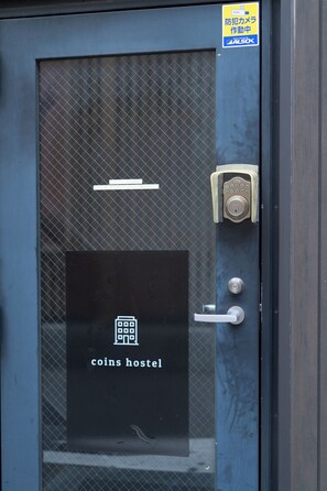A door with a lock, a keypad, and a sign indicating 'coins hostel'.