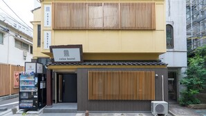 Um hostel com máquina de vendas automática, uma placa de sinalização e um pequeno aparelho de ar condicionado na parte externa.