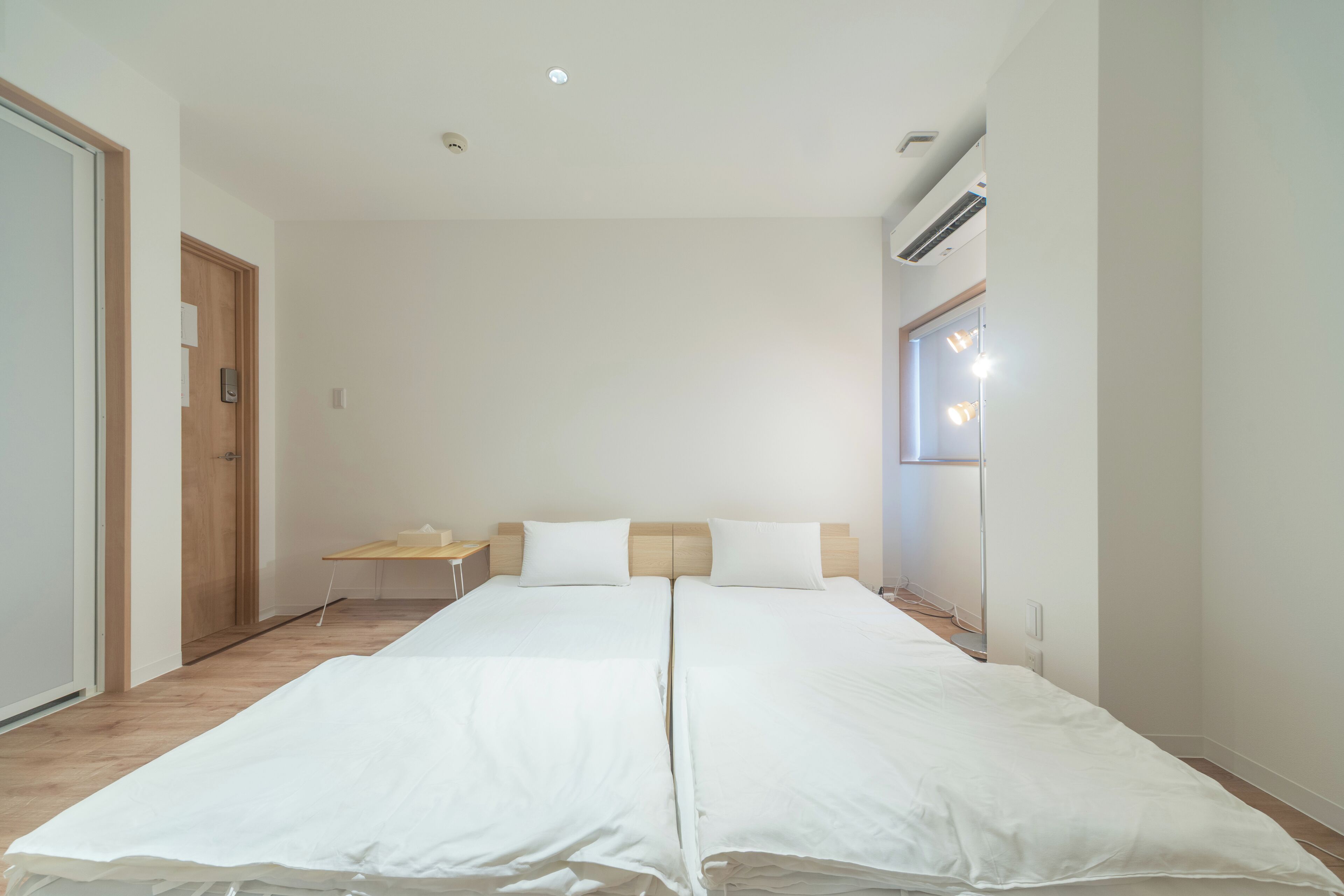 A double bed with white linens, a wooden headboard, a small bedside table, and a nightstand.
