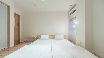 A double bed with white linens, a wooden headboard, a small bedside table, and a nightstand.