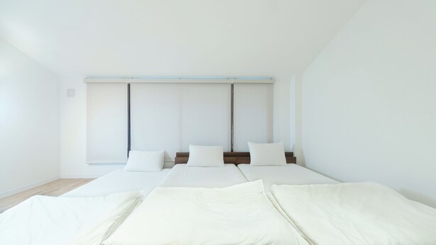 Quarto de hotel com duas camas, uma cabeceira de madeira e uma janela grande com persianas.