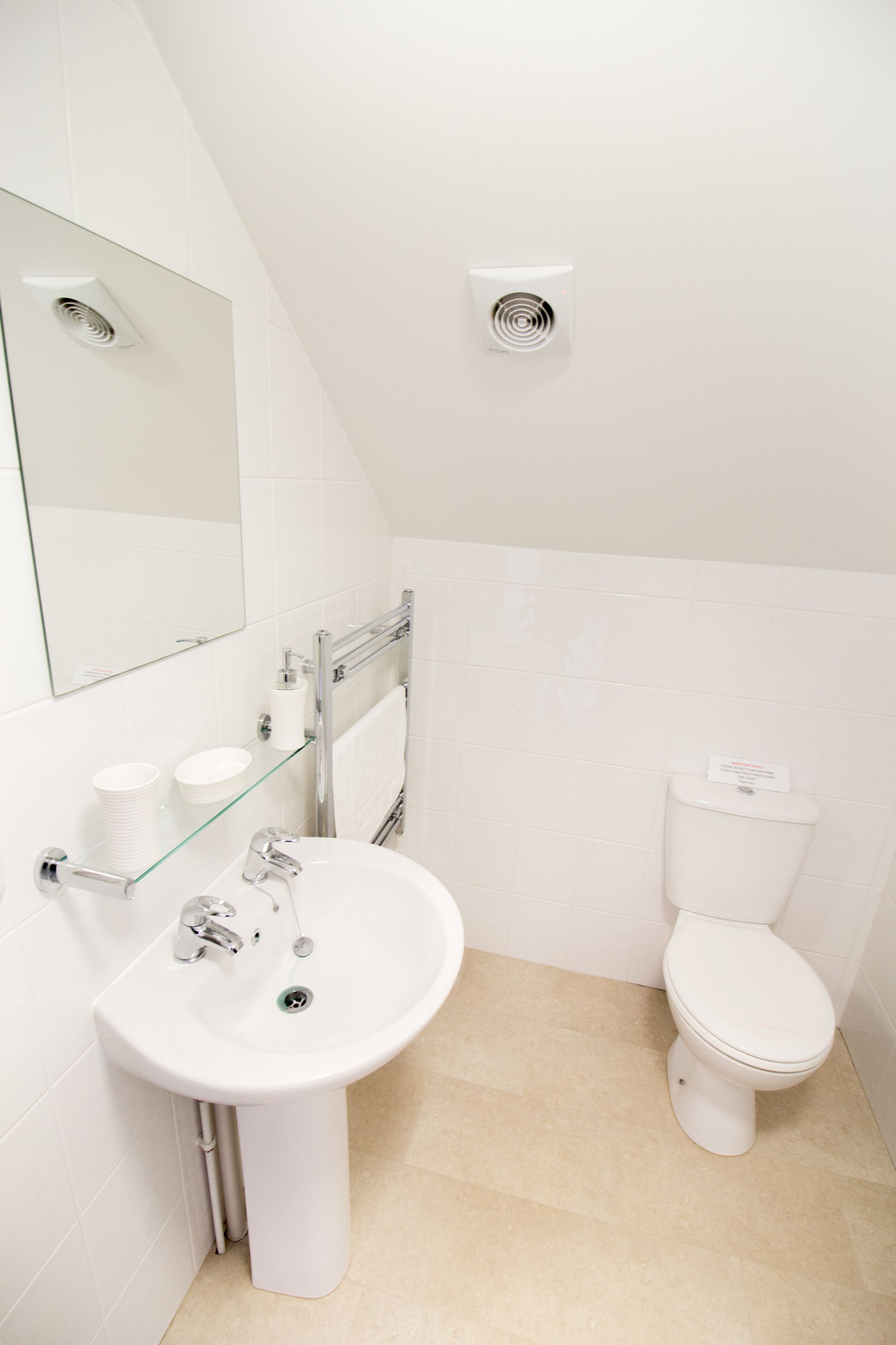 A modern bathroom with a white sink, mirror, and toilet.