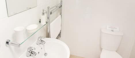 Een moderne badkamer met een witte wastafel, spiegel en toilet.
