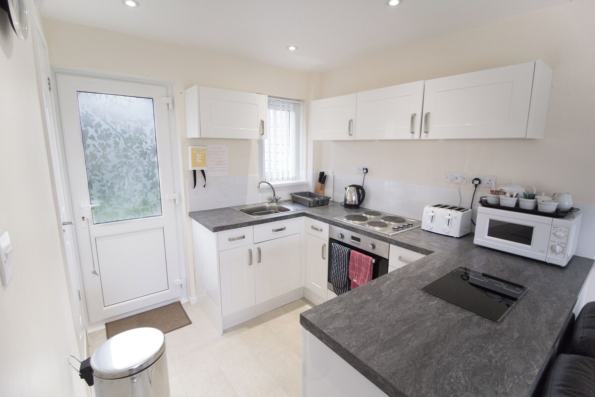 A modern kitchen with white cabinets, a built-in oven, a microwave, and a toaster.