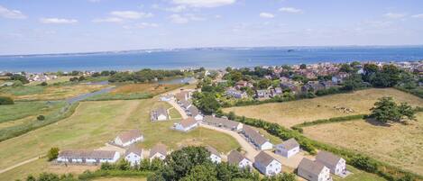 An aerial view of a coastal village with houses, a river, and a sea view.