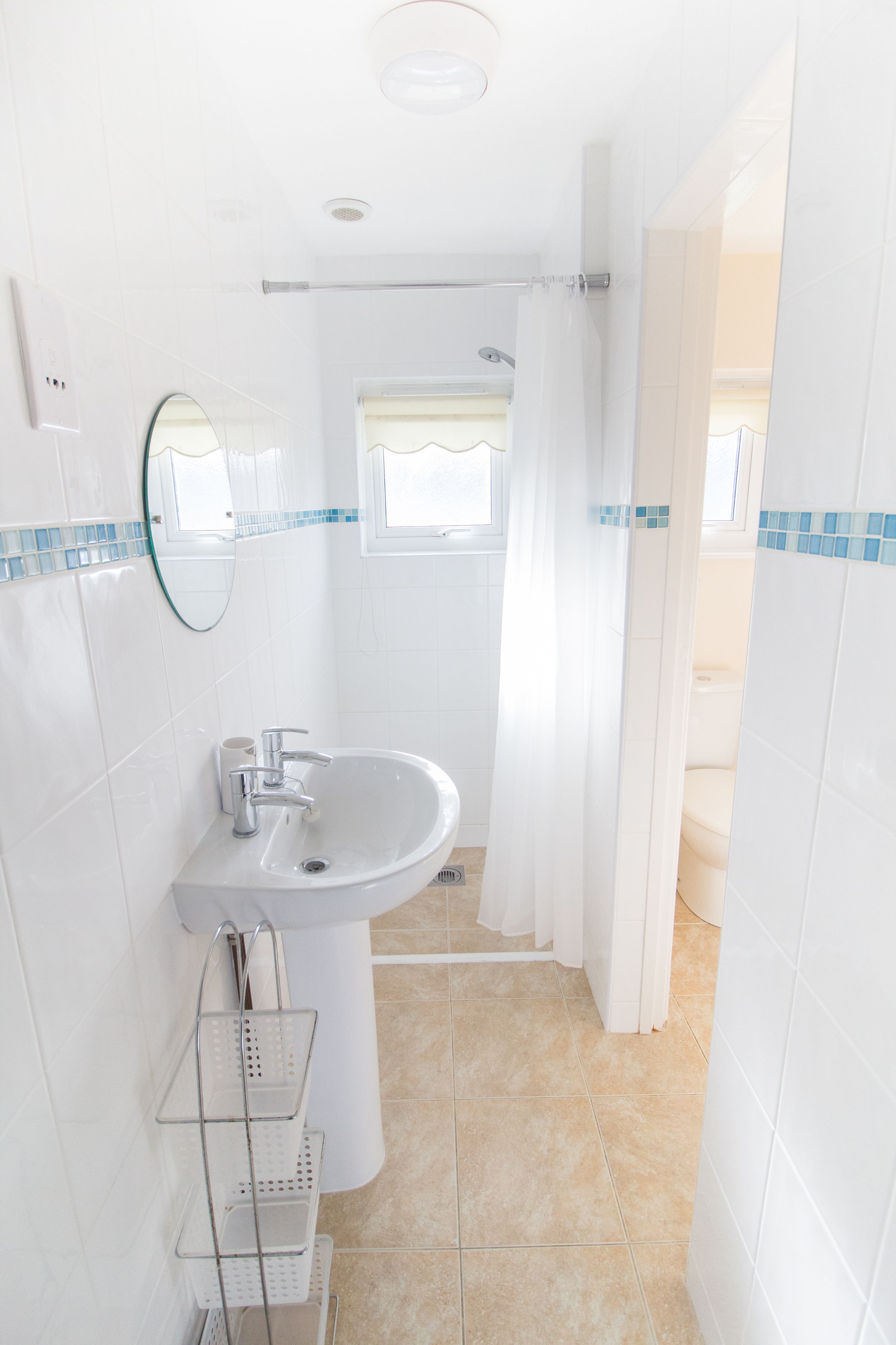 A bathroom with a sink, mirror, and shower curtain.
