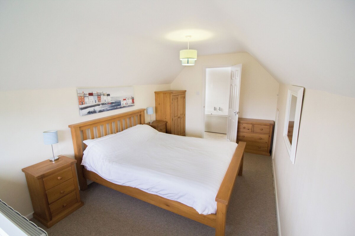 A bedroom with a wooden bed, a nightstand, a dresser, a wardrobe, and a painting on the wall.