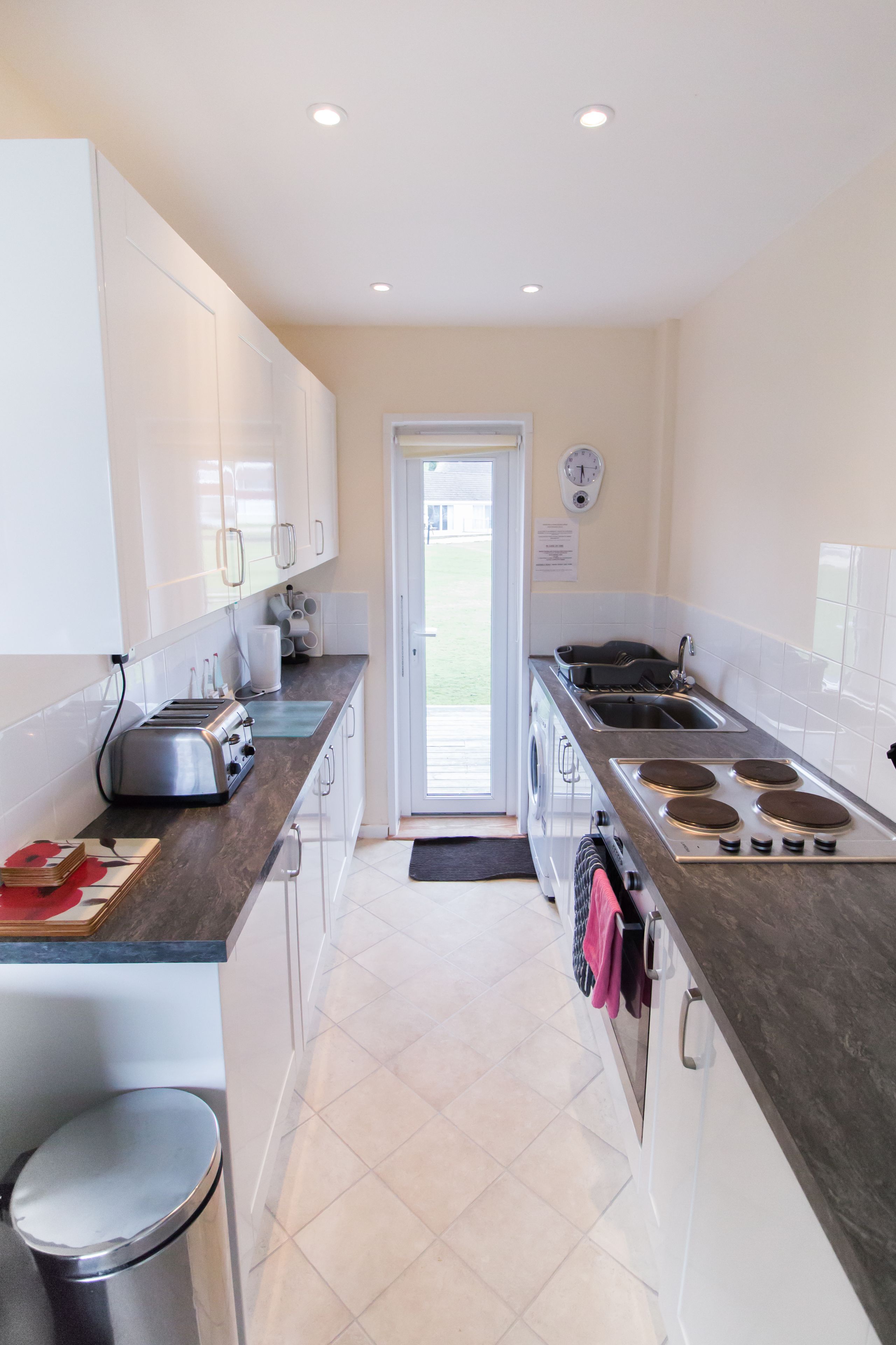 A modern kitchen with white cabinets, a stainless steel sink, a stove, and a toaster.