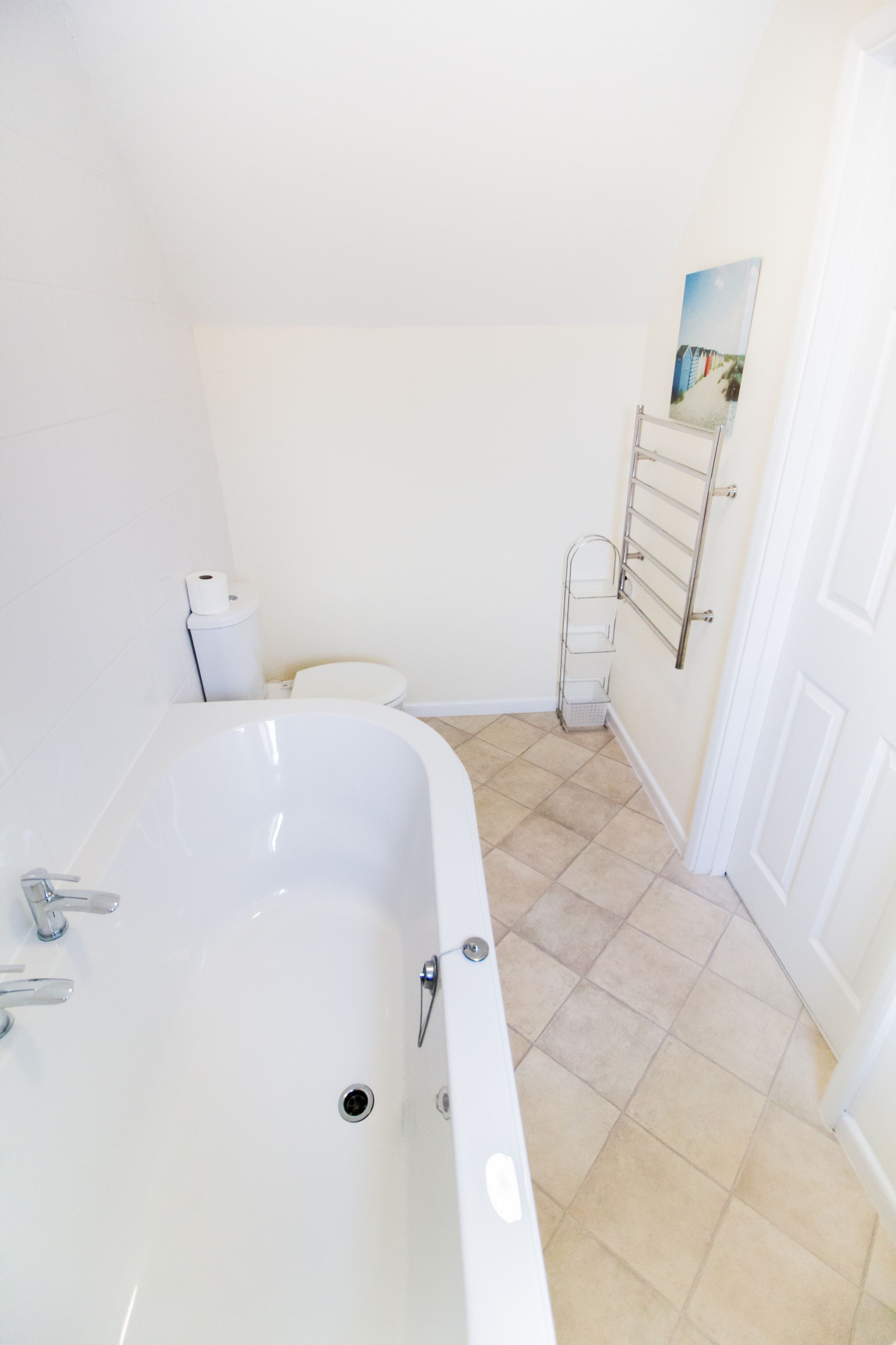 A bathroom with a bathtub, toilet, and a towel rack.