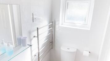 A bathroom with a white sink, toilet, and glass shower enclosure.