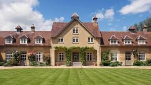 A large, symmetrical building with a central entrance, multiple windows, and a well-maintained lawn in front. - Cheltenham Cottage (Chipping Norton)
