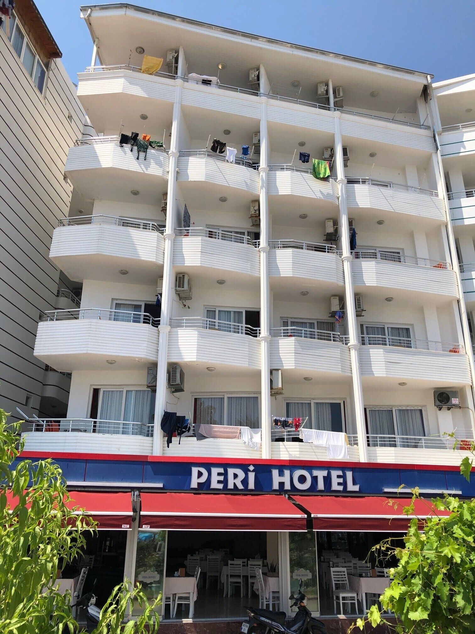 A multi-story hotel with balconies, air conditioning units, and a visible restaurant area at the ground level.