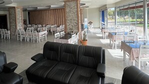 Un vestíbulo amplio con un sofá de cuero negro, un candelabro y un comedor con sillas y mesas blancas.