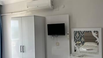Ein Zimmer mit einem weißen Kleiderschrank, einem flachbildfernseher an der Wand und einem kleinen Kühlschrank.