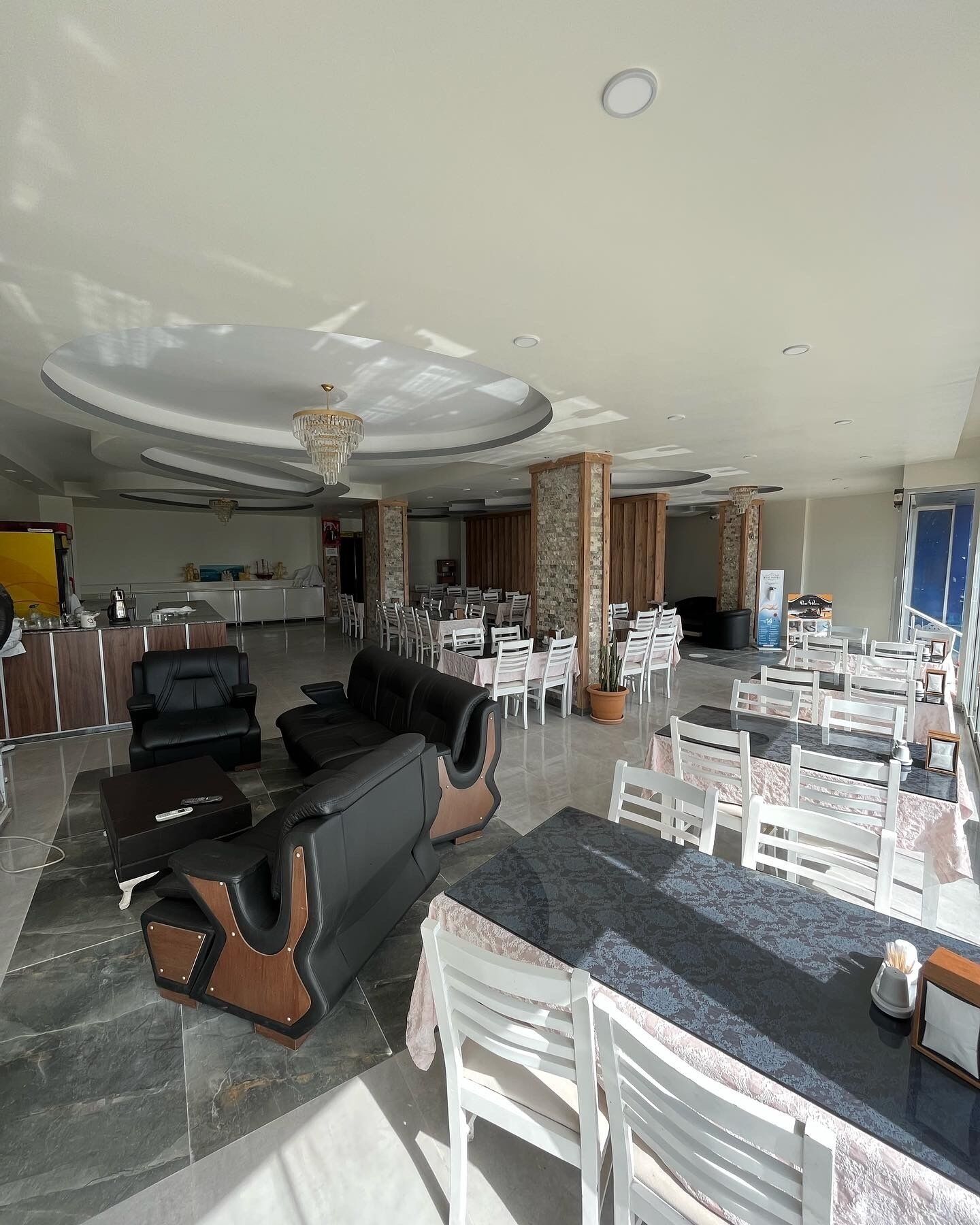 Een ruime lobby met een modern design, met een zithoek met banken en stoelen, een receptiebalie en een kroonluchter.