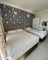 A hotel room with two beds, a wardrobe, and a mirror.