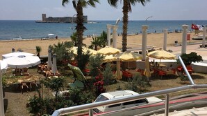 Vista de una playa con palmeras, sombrillas y asientos al aire libre.