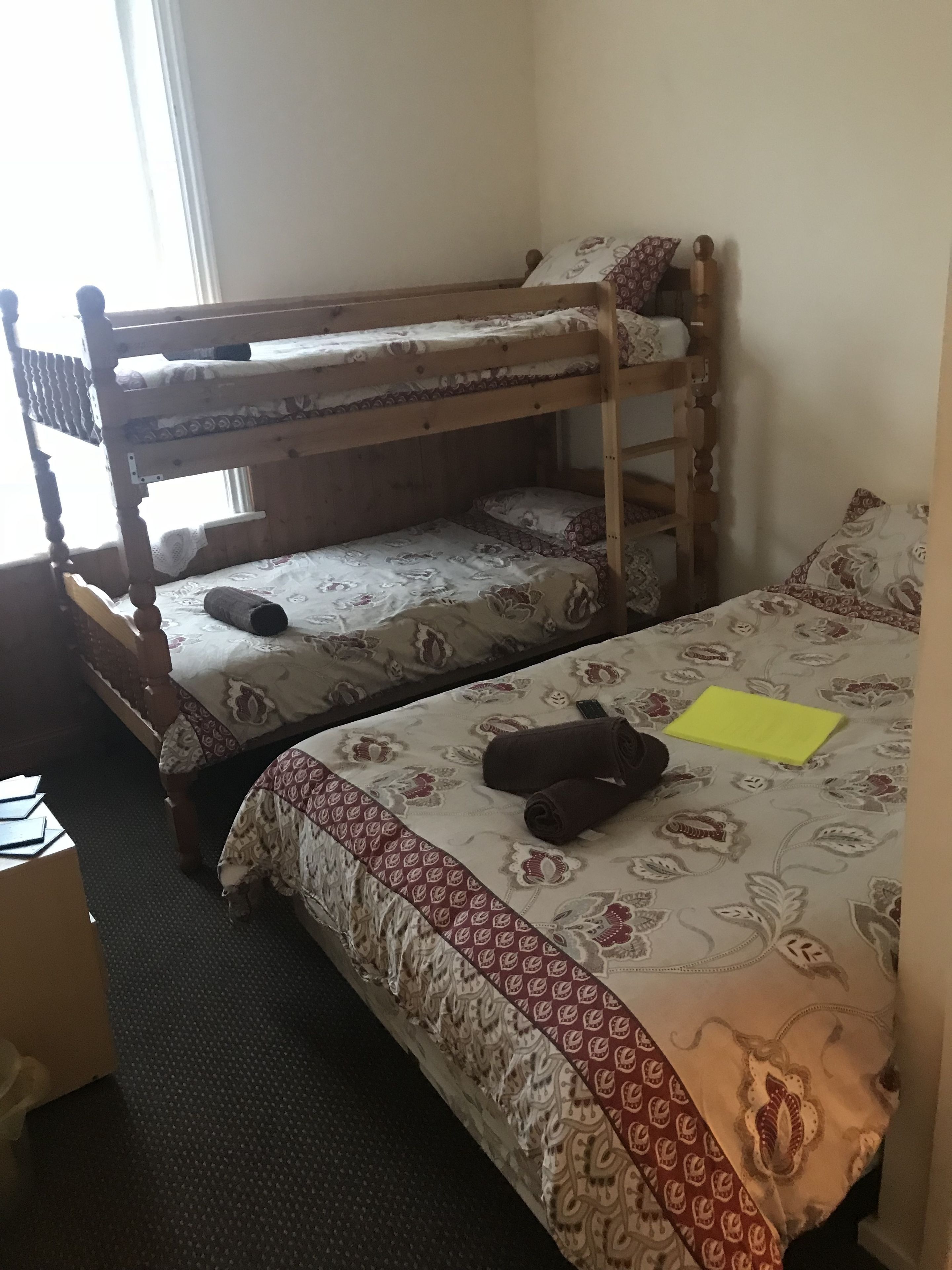 A bunk bed room with patterned bedding and a yellow note on the lower bunk.
