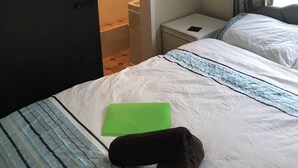 Quarto de hotel com cama, mesa de cabeceira, banheiro visível por uma porta aberta e janela com cortinas.