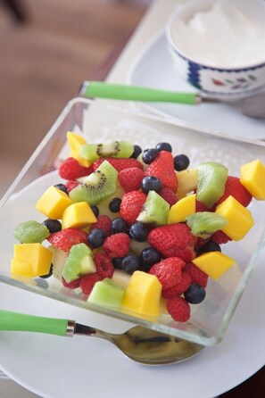 A clear glass bowl filled with a variety of fresh fruits including strawberries, blueberries, raspberries, kiwi, and mango chunks. - Hedingham Old Pottery (Halstead)