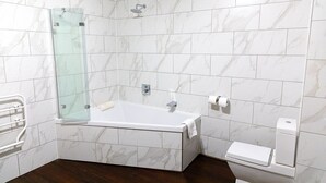 A modern bathroom with a glass-enclosed shower, a freestanding bathtub, and a toilet. - The City Rooms (Leicester)