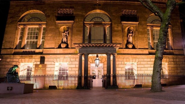 A historic building with arched windows and a central entrance, surrounded by a black iron fence. - The City Rooms (Leicester)