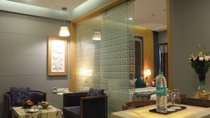 Habitación de hotel moderna con zona de comedor, sofá y mesa dispuesta con una botella de agua y vasos.