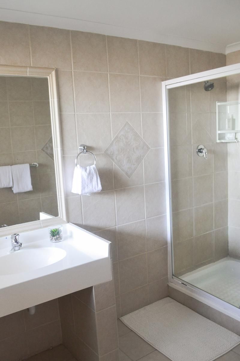 A bathroom with a white sink, a glass shower enclosure, and a tiled floor.