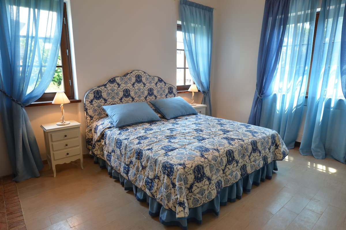 A bedroom with a bed, nightstands, and curtains.