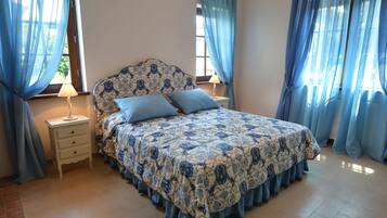 A bedroom with a bed, nightstands, and curtains.