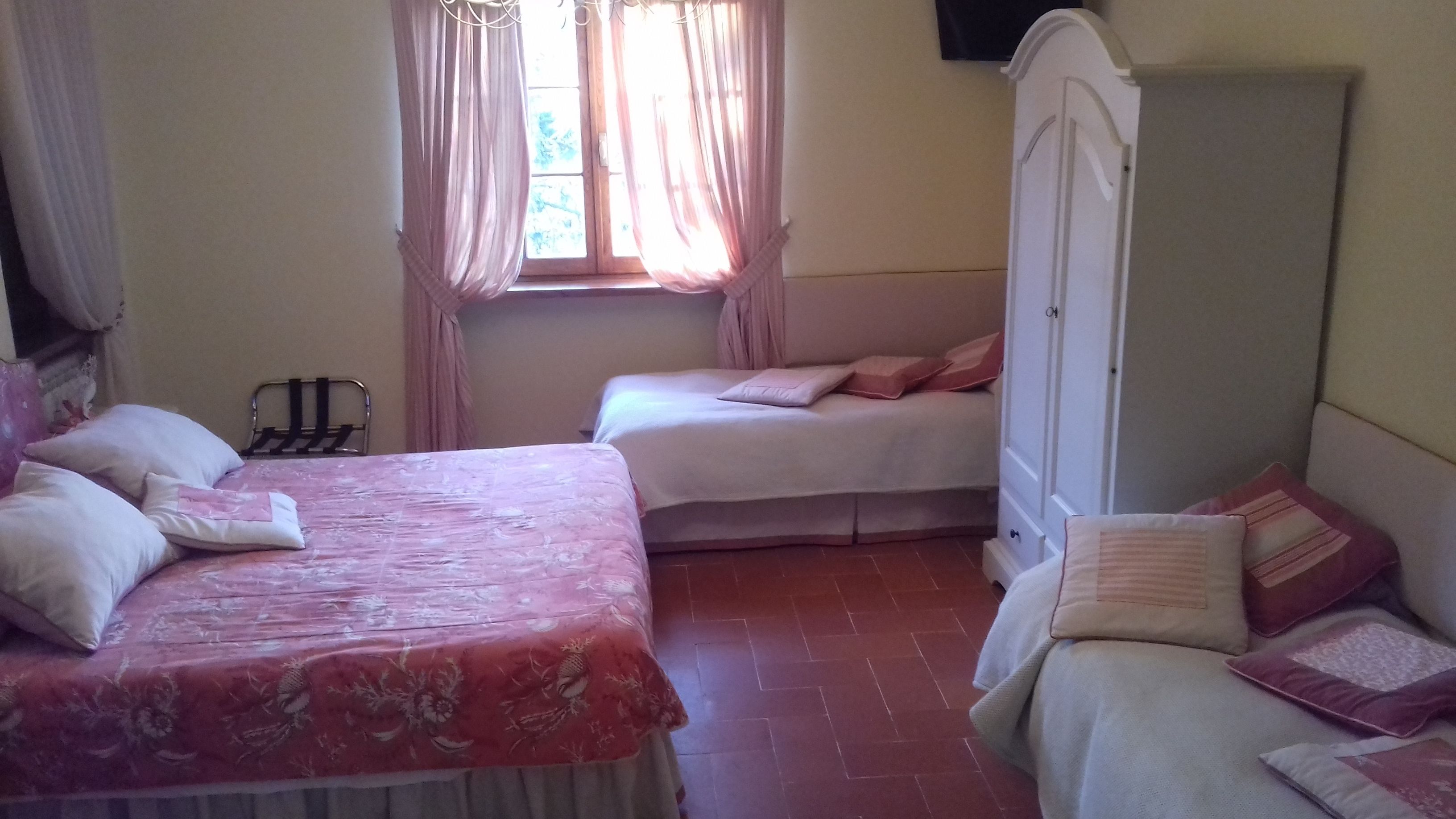 A bedroom with two beds, a wardrobe, and a window with curtains.