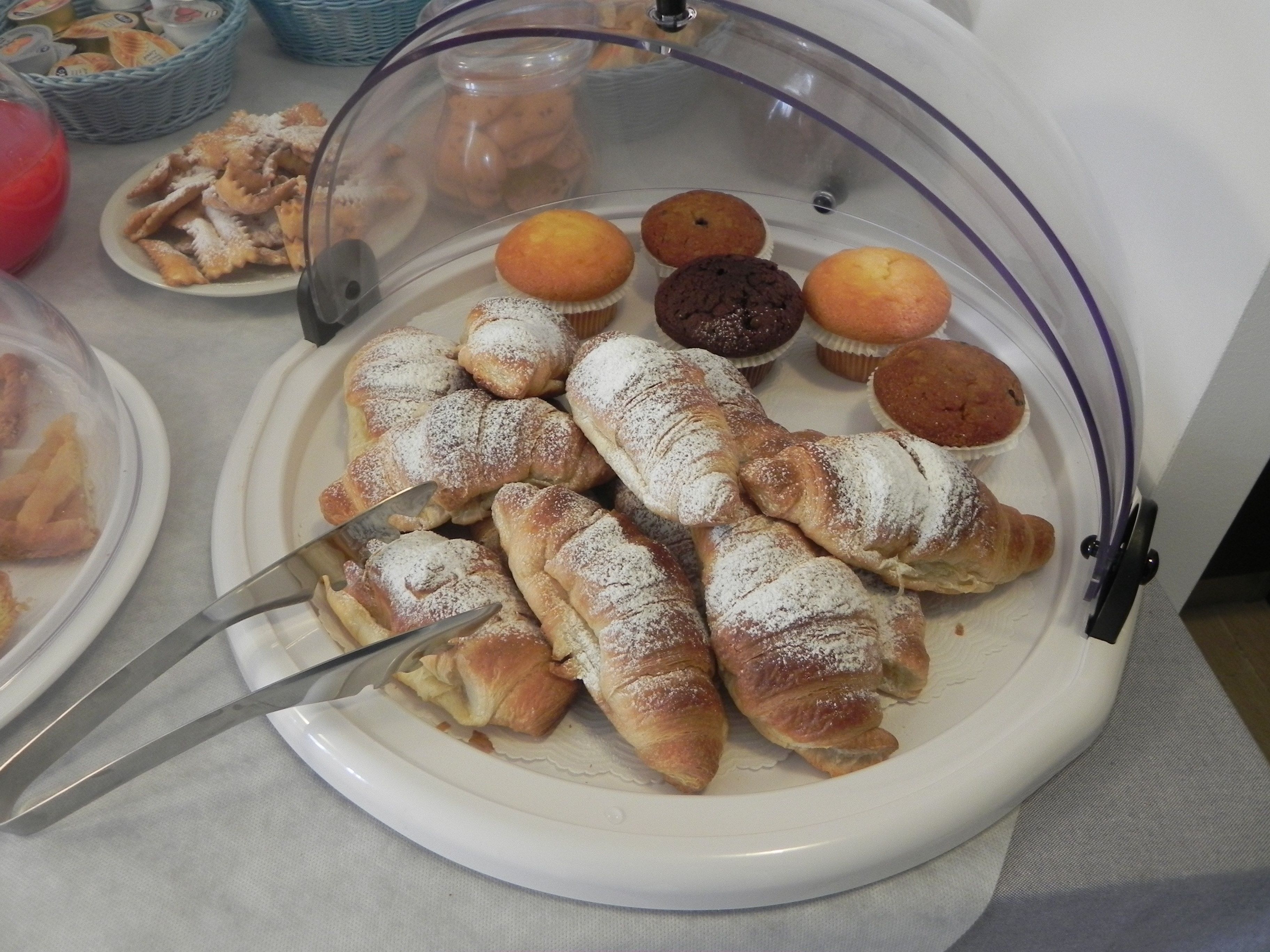 Esposizione di dolci, tra cui croissant e muffin, con un coltello su un piatto.