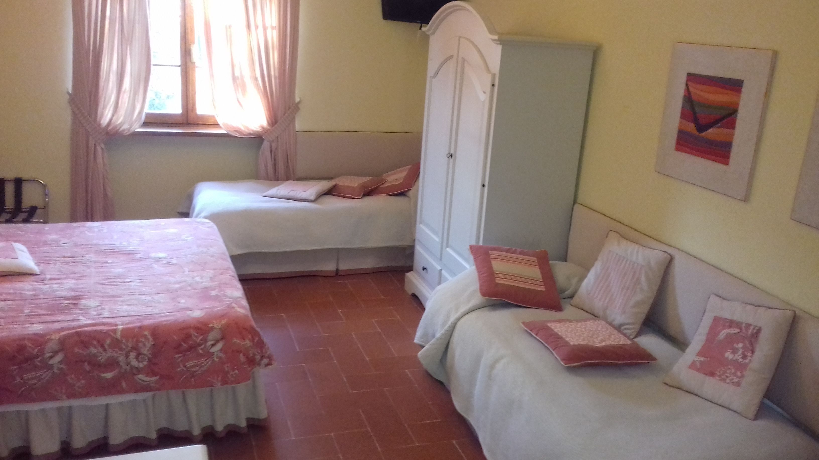 A bedroom with two beds, a wardrobe, and a window with curtains.