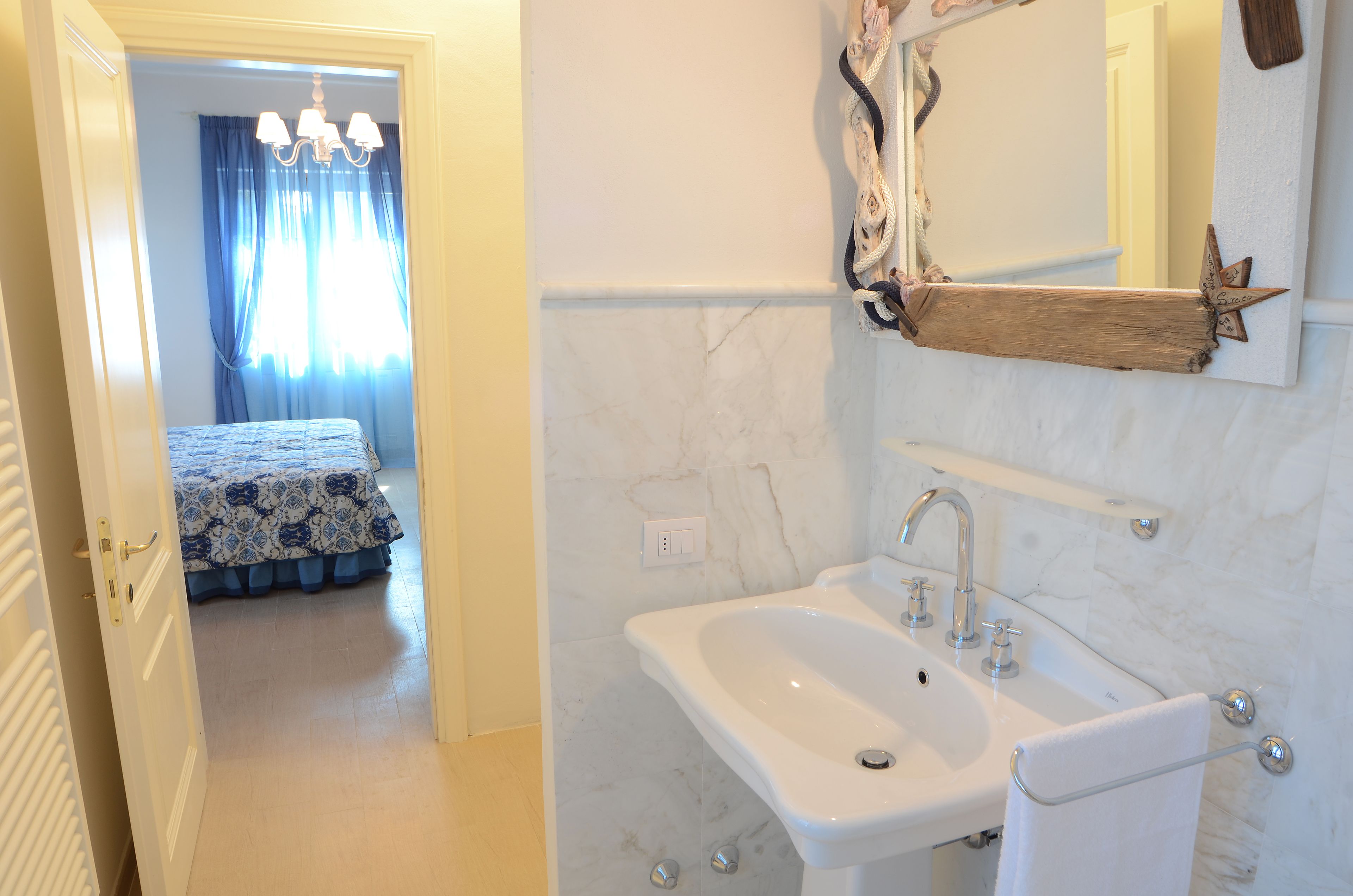 A bathroom with a white sink, mirror, and marble walls.