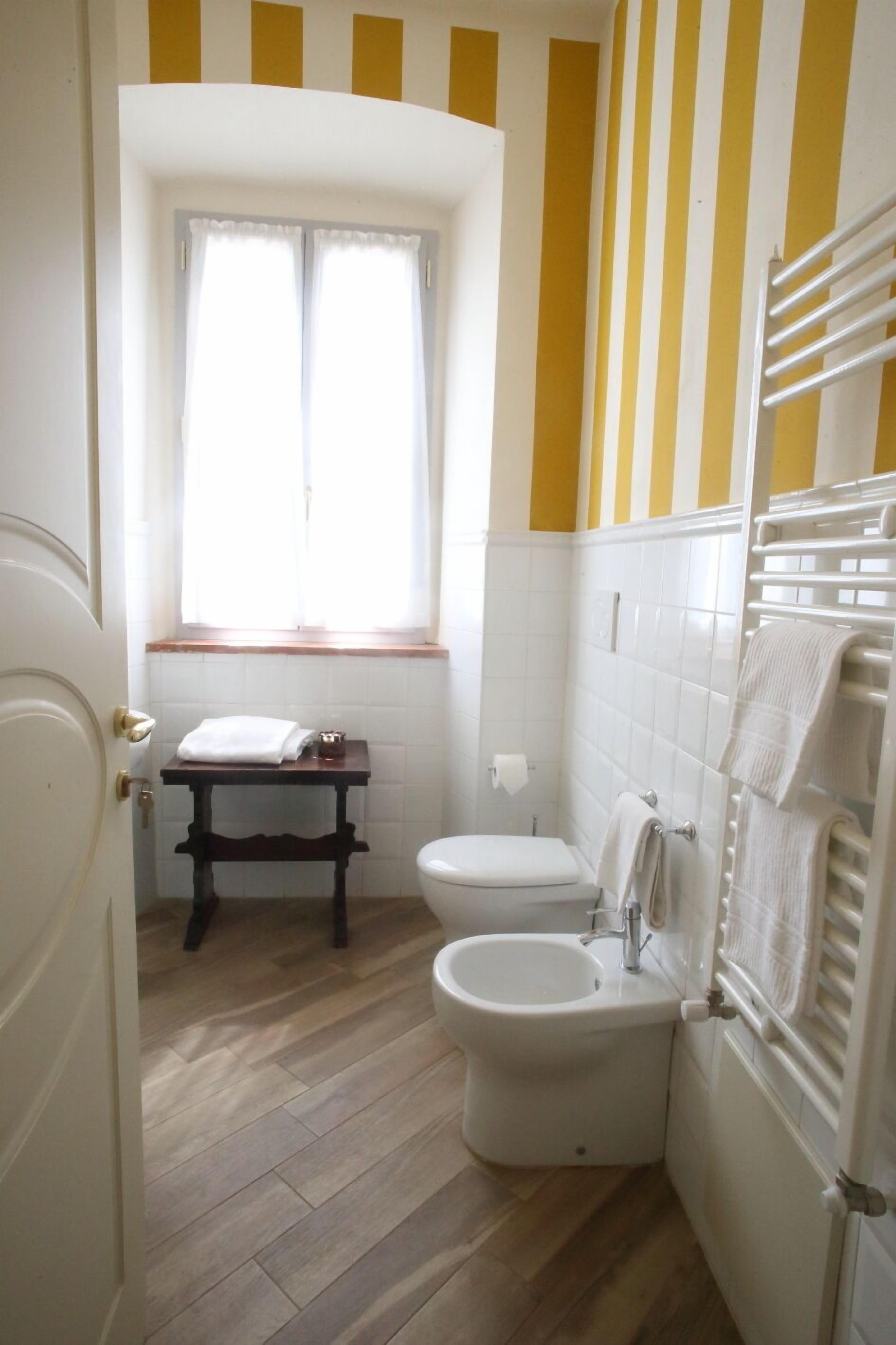 Een badkamer met toilet, bidet en een klein tafeltje met een handdoek.