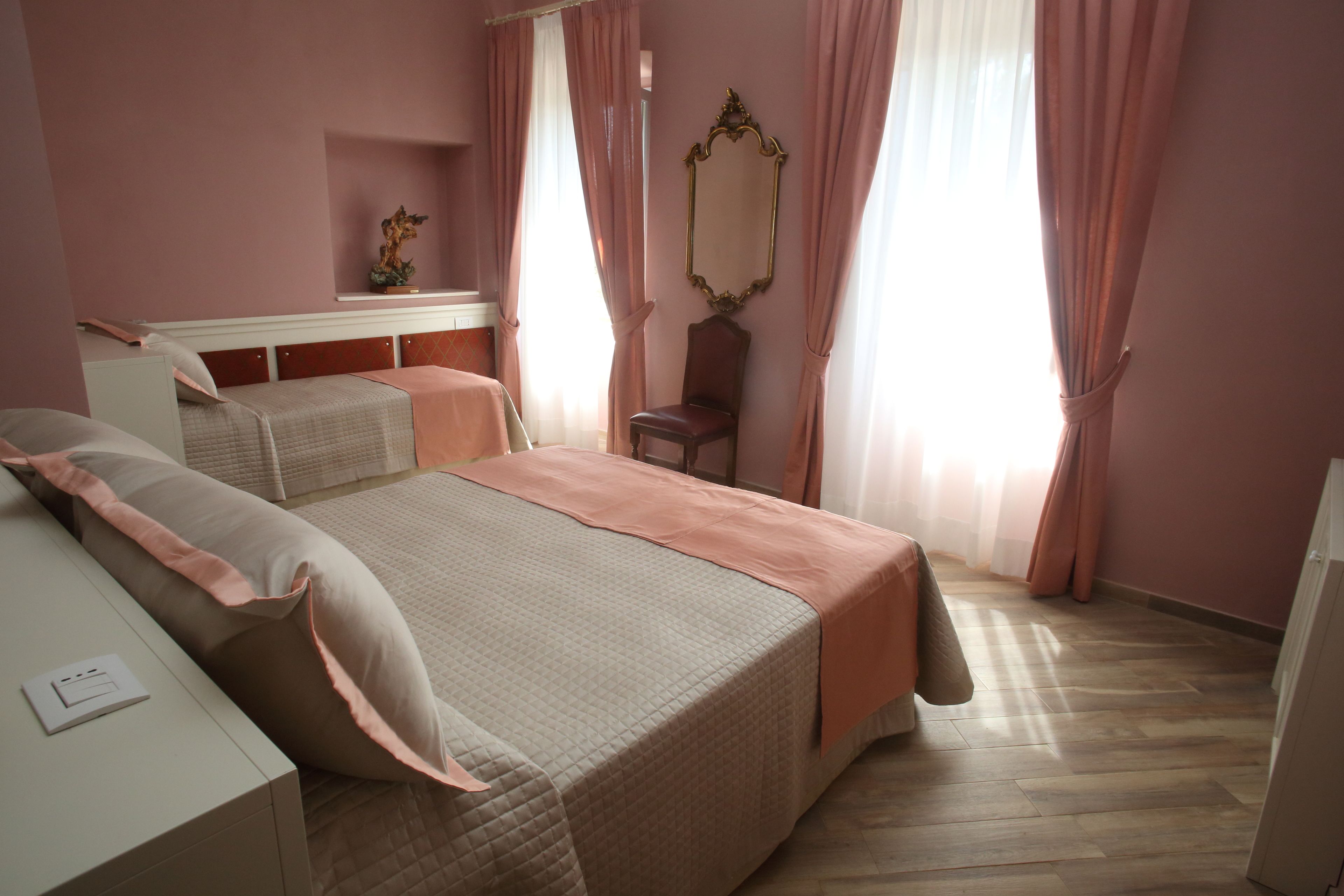 Ein Schlafzimmer mit einem Bett, Nachttischen, einem Sessel, einem Spiegel und einem Regal mit einem dekorativen Gegenstand.
