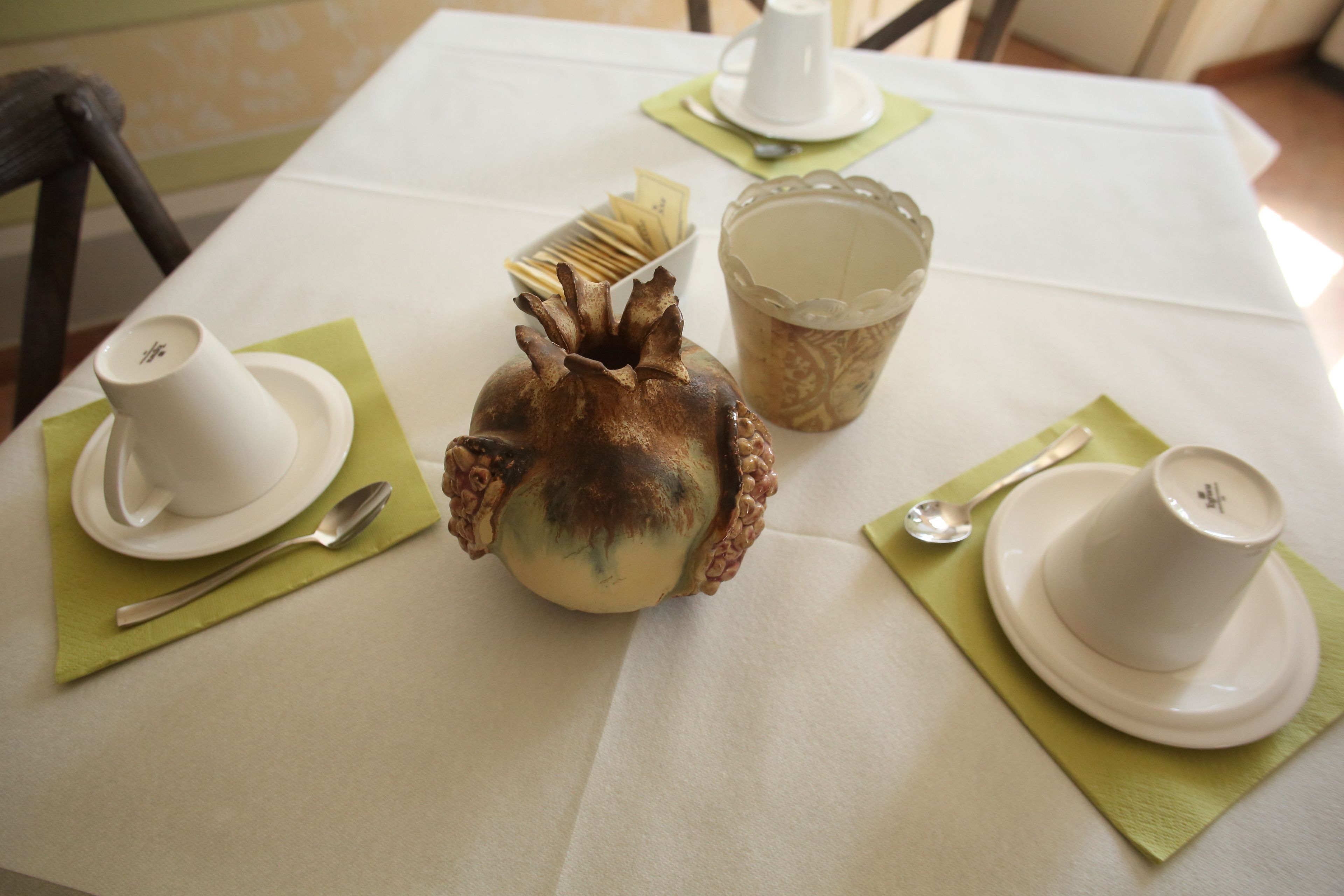 Una mesa con tazas, platillos y un objeto decorativo.